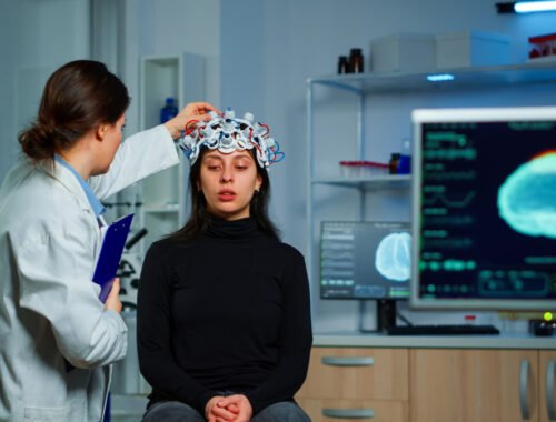 Neurological doctor cheking eeg headset explaining to patient diagnosis of disease and treatment for nervous system. Scientist researcher analysing brain scan and tomography on monitor in lab